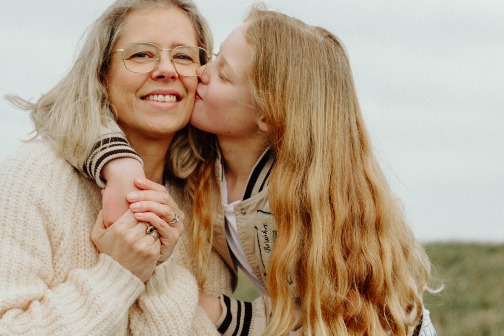 Moeder en dochter op de foto op een mooie buitenlocatie in Zwolle. Dochter geeft moeder een kus. 