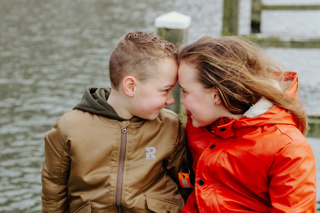 Broer en zus op de foto bij water. 