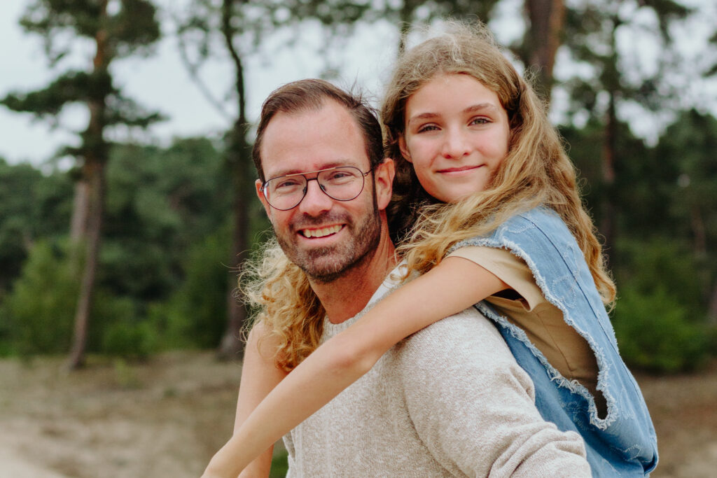 Gezins fotoshoot. Vader met dochter op zijn rug.