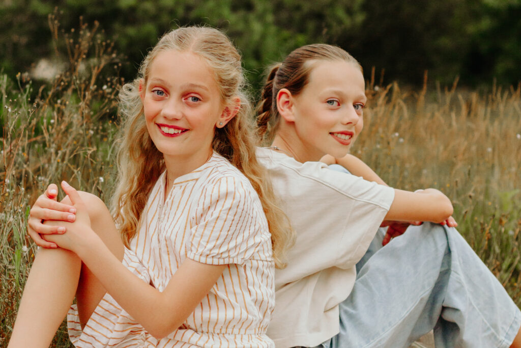 Twee vriendinnetjes in het gras tijdens een fotoshoot.